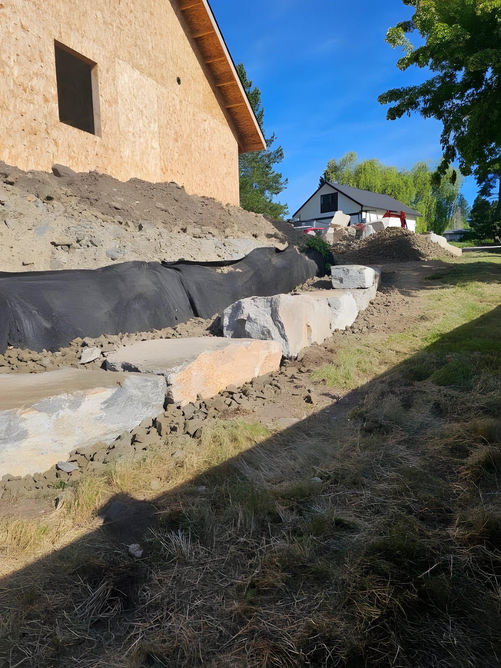 First row of large boulders set along a slope with landscape fabric behind them