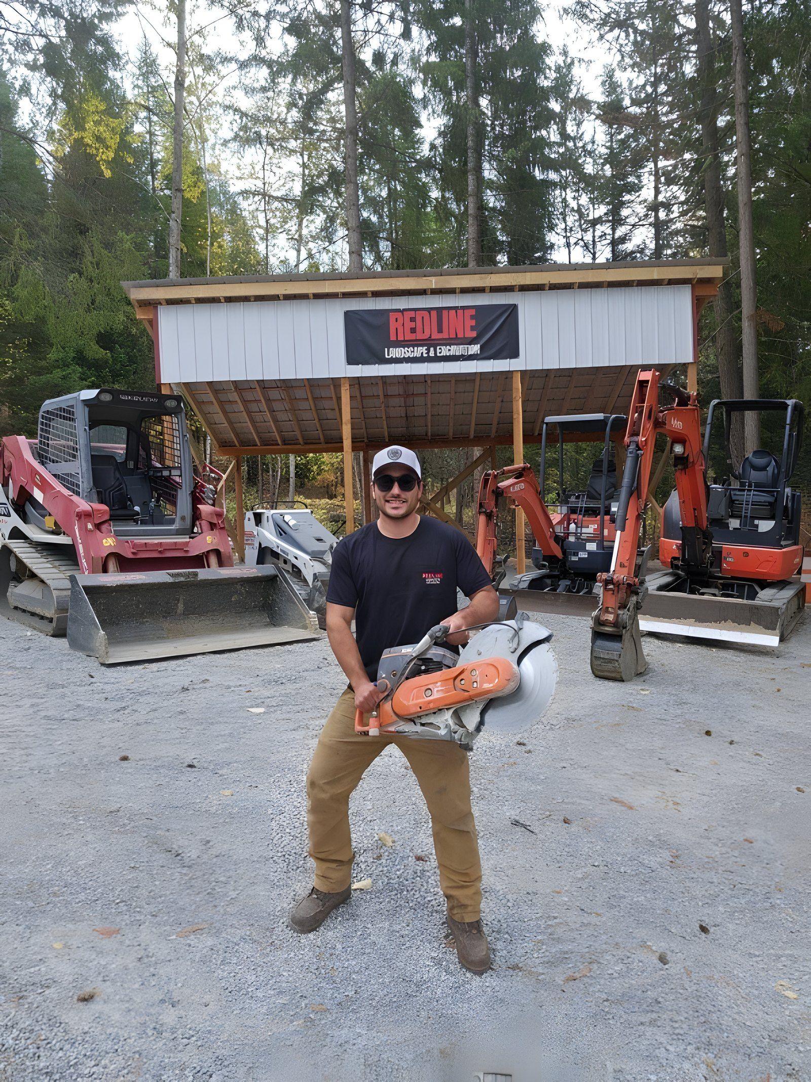 Peter LaBarbera holding a concrete saw in front of his skid steer and mini excavators at the Redline shop