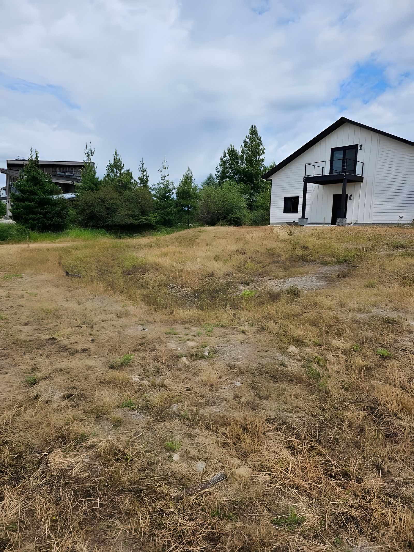 Dry, bare slope below a white two-story house before work started